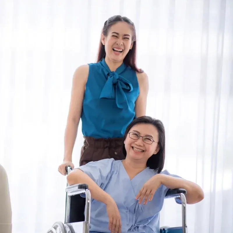 A senior patient and her daughter holding hands